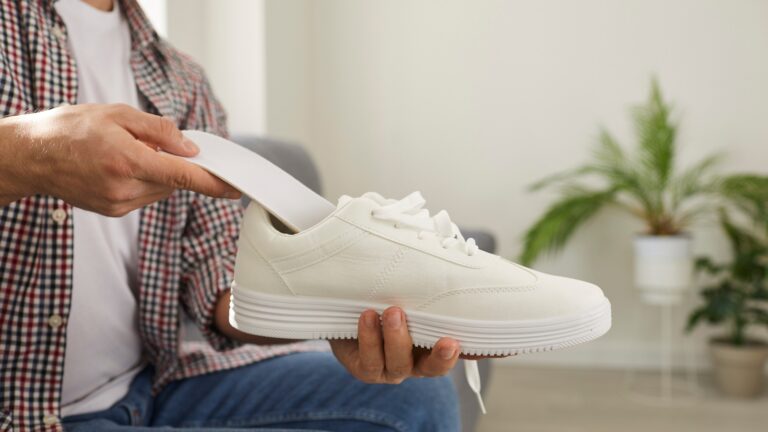 Mann legt neue orthopädische Einlegesohle mit Fußgewölbestütze in bequemen Schuh