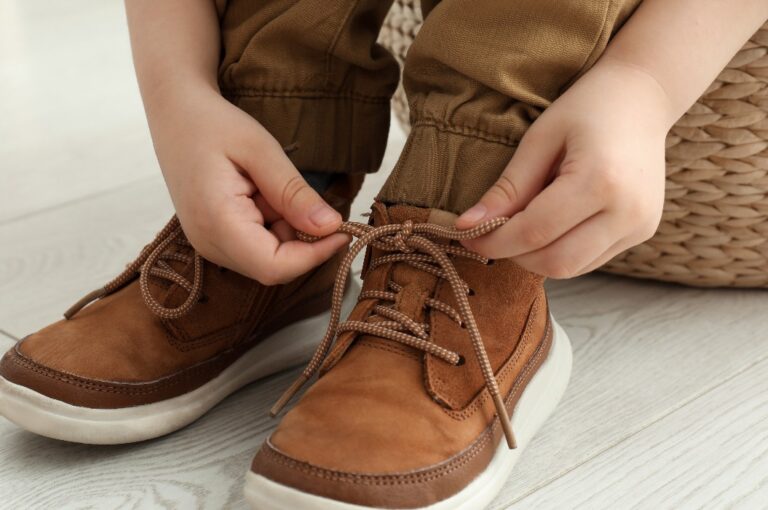 Ein kleiner Junge, der sich zu Hause die Schnürsenkel bindet