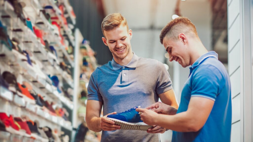 Zwei Männer, die sich in einem Sportgeschäft für neue Sportschuhe entscheiden