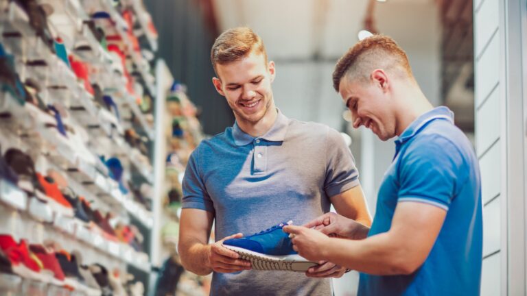 Zwei Männer, die sich in einem Sportgeschäft für neue Sportschuhe entscheiden